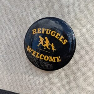 schwarzer Button mit Refugees welcome-Aufschrift