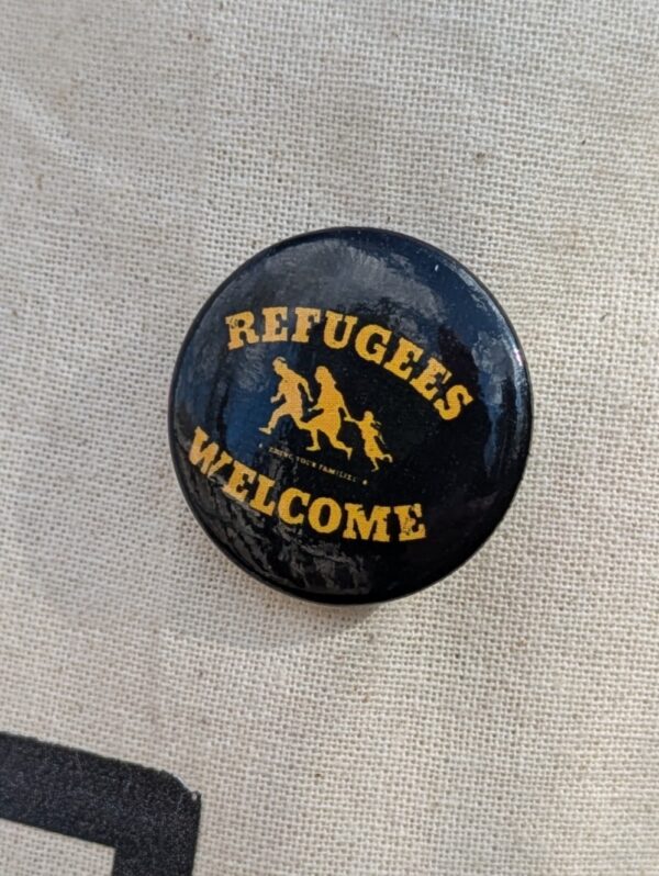 schwarzer Button mit Refugees welcome-Aufschrift