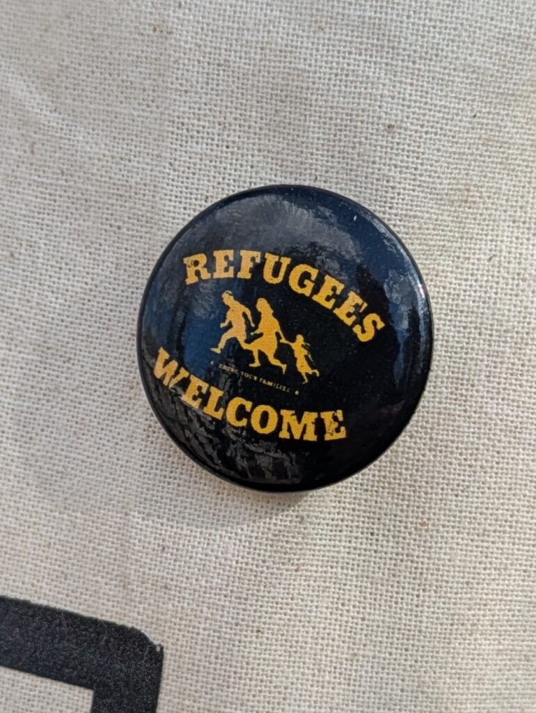 schwarzer Button mit Refugees welcome-Aufschrift