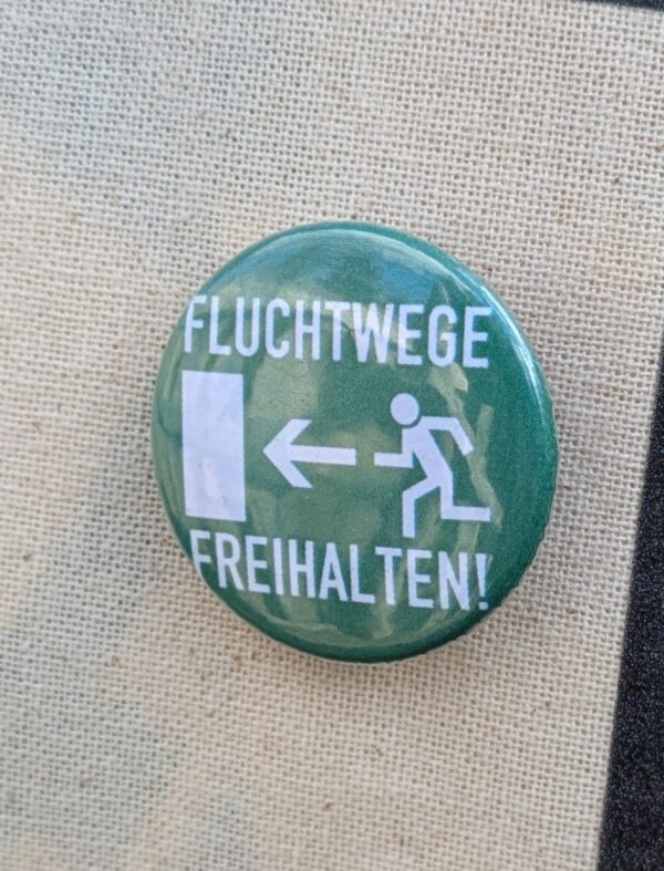 Button weiße Schrift 'Fluchtwege freihalten' auf grün und Symbol für Fluchtweg