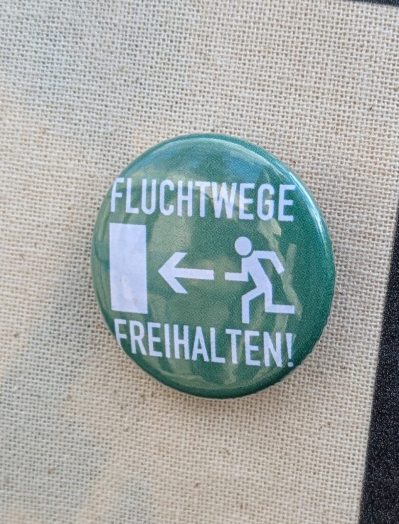 Button weiße Schrift 'Fluchtwege freihalten' auf grün und Symbol für Fluchtweg
