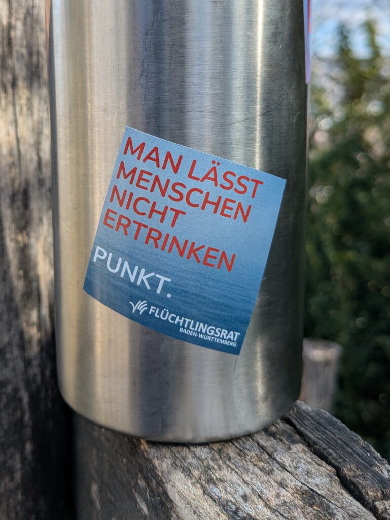 Sticker mit Aufschrift 'Man lässt Menschen nicht ertrinken' mit Meer
