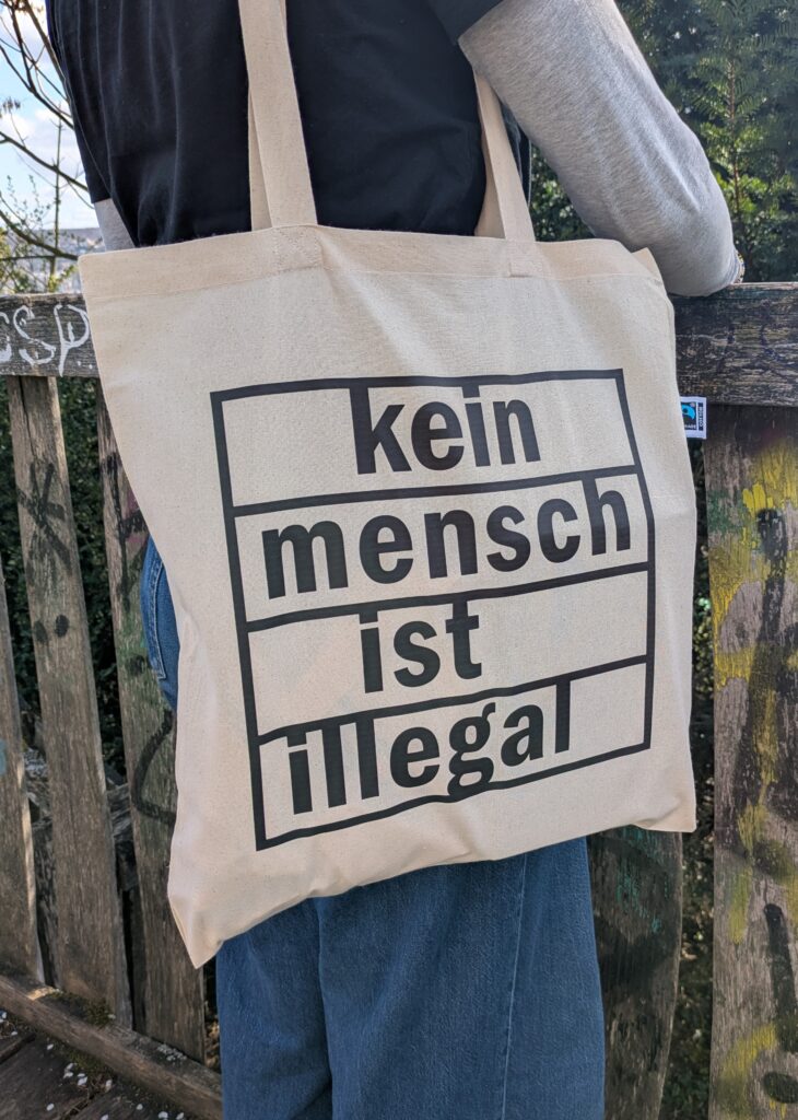 Naturfarbene Tasche mit chwarzem Aufdruck 'Kein Mensch ist illegal'